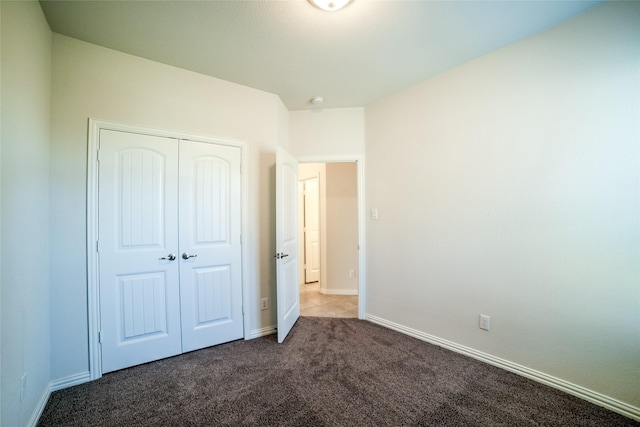 unfurnished bedroom with a closet, baseboards, and dark carpet