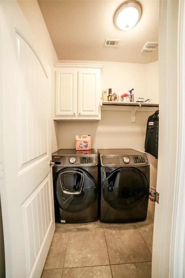 clothes washing area with a textured ceiling, cabinets, and independent washer and dryer