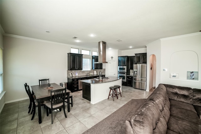 interior space featuring open floor plan, a kitchen breakfast bar, island exhaust hood, arched walkways, and stainless steel appliances