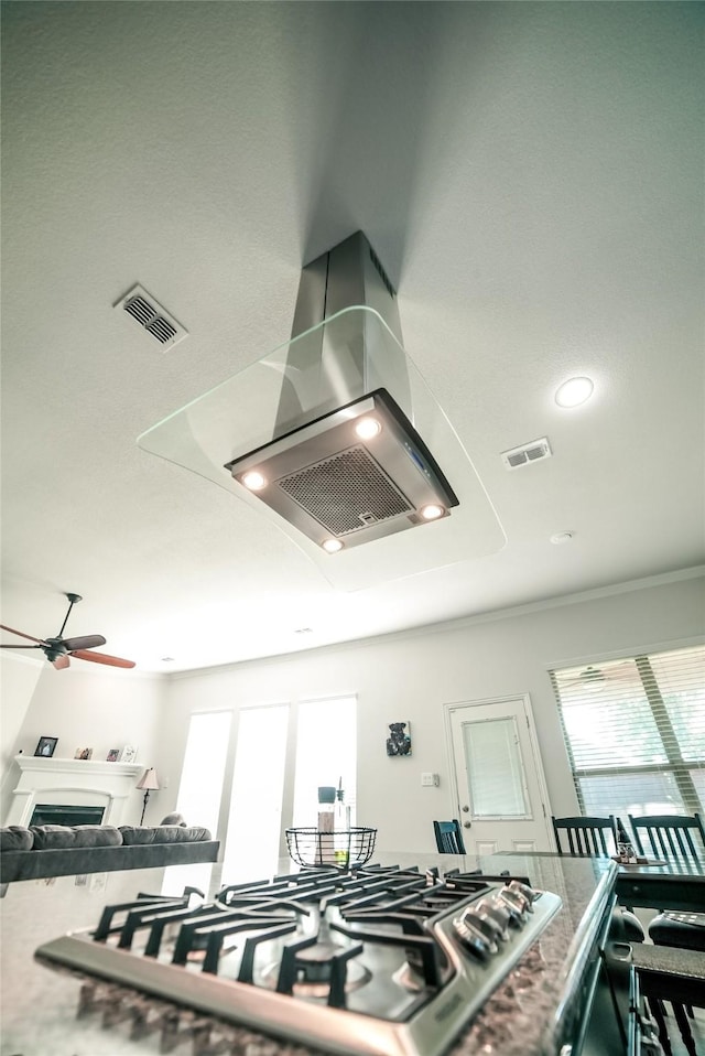 kitchen featuring visible vents, a fireplace, ceiling fan, and stainless steel gas stovetop