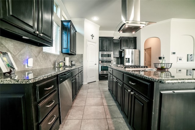 kitchen with stainless steel appliances, dark cabinetry, island range hood, and ornamental molding