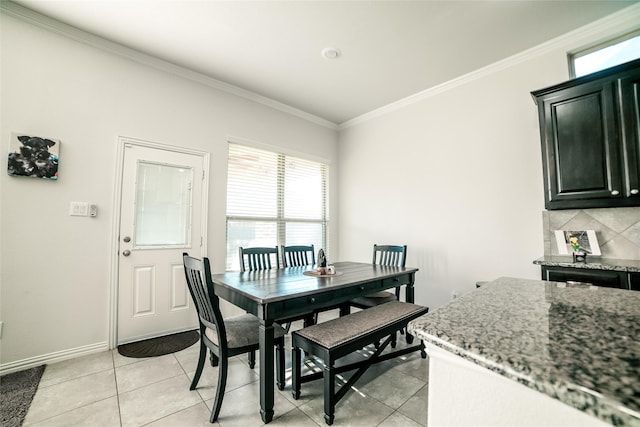 dining room with light tile patterned floors, crown molding, and baseboards