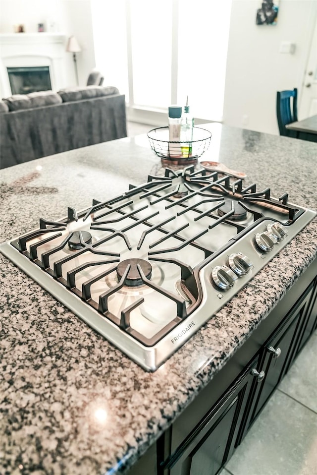 details with light stone counters, a glass covered fireplace, and stainless steel gas stovetop