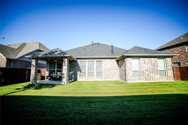 back of property with a patio, a fenced backyard, a shingled roof, a lawn, and brick siding