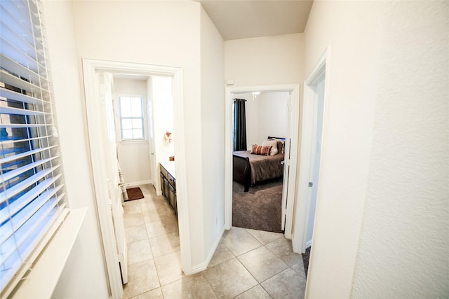 corridor featuring light tile patterned floors and baseboards