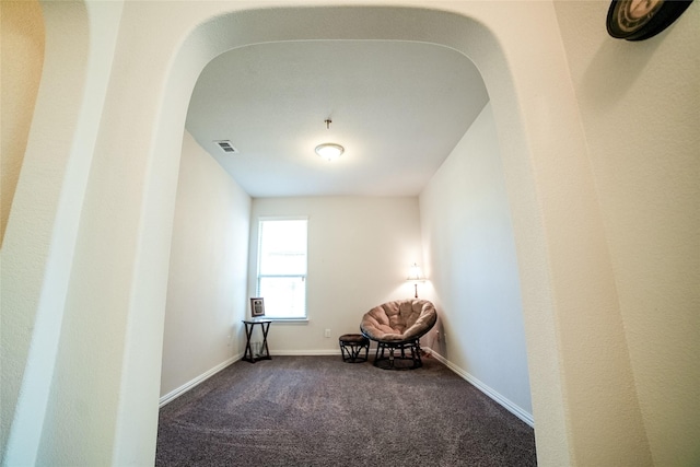 unfurnished room featuring arched walkways, visible vents, dark colored carpet, and baseboards