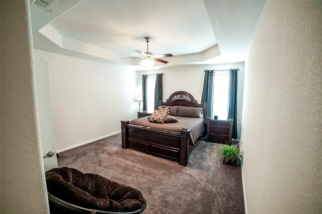 bedroom with carpet flooring, ceiling fan, and a tray ceiling