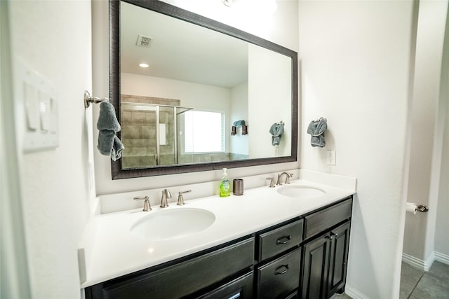 bathroom with a sink, visible vents, tiled shower, and double vanity