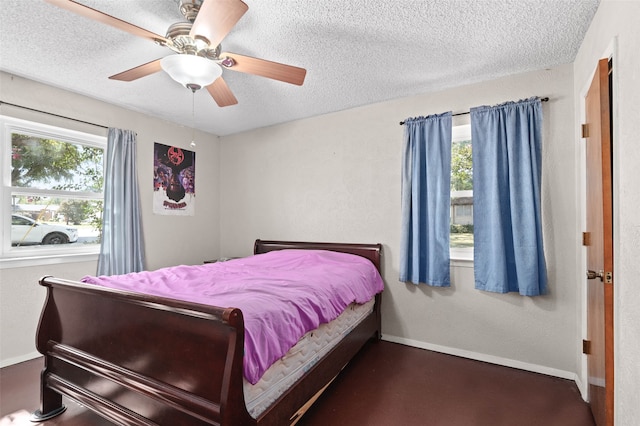 bedroom with a textured ceiling, ceiling fan, and multiple windows