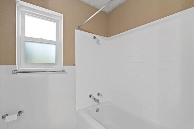 bathroom featuring a textured ceiling and tiled shower / bath combo