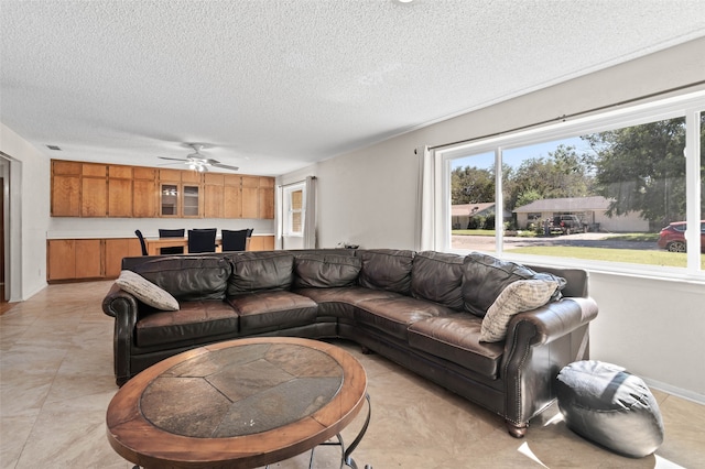 living room with ceiling fan and a textured ceiling