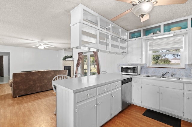 kitchen with a brick fireplace, sink, ceiling fan, appliances with stainless steel finishes, and light hardwood / wood-style floors