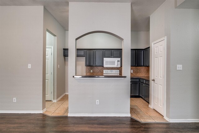 kitchen featuring hardwood / wood-style floors, decorative backsplash, and white appliances