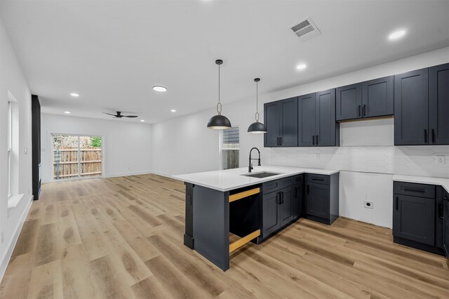 kitchen featuring light wood-type flooring, decorative light fixtures, sink, kitchen peninsula, and ceiling fan