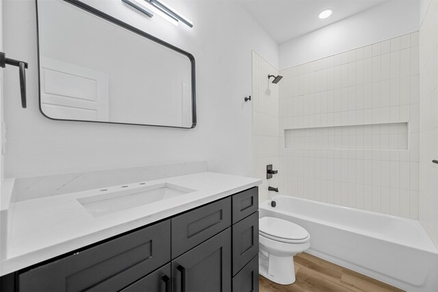 full bathroom with tiled shower / bath, vanity, toilet, and hardwood / wood-style floors