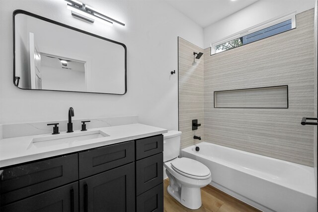 full bathroom featuring tiled shower / bath, vanity, toilet, and wood-type flooring