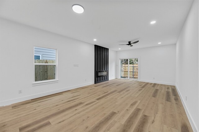 unfurnished living room featuring light wood-type flooring, a healthy amount of sunlight, and ceiling fan