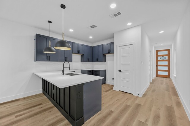 kitchen featuring light wood-type flooring, sink, kitchen peninsula, pendant lighting, and tasteful backsplash