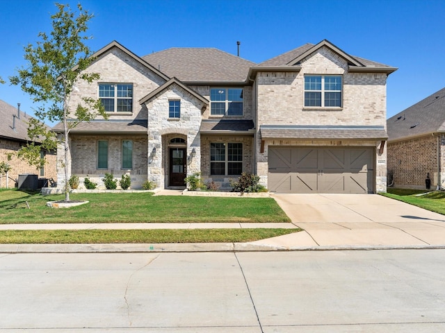 view of front of property featuring a front yard, a garage, and central AC unit