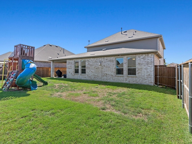 rear view of property with a lawn and a playground