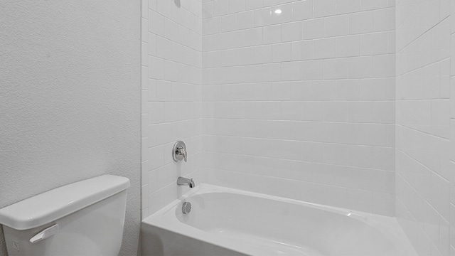 bathroom featuring tiled shower / bath combo and toilet