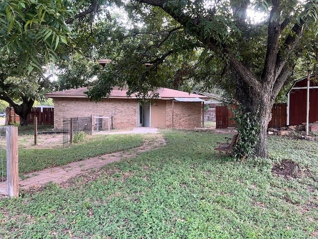 view of front of house featuring a storage unit and a front yard