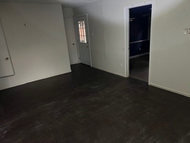 empty room featuring dark wood-type flooring and a textured ceiling