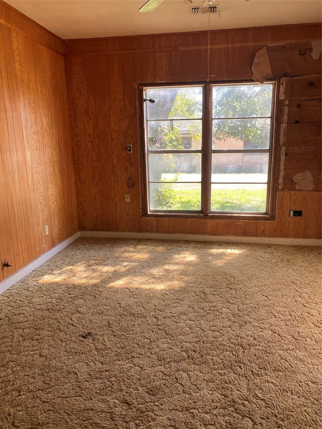 unfurnished room with wood walls, ceiling fan, and carpet floors