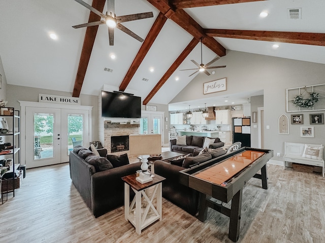 living room with a fireplace, high vaulted ceiling, ceiling fan, french doors, and light hardwood / wood-style floors