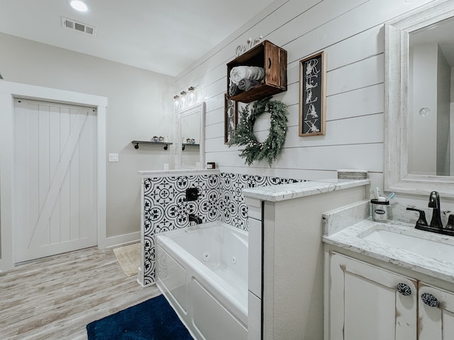 bathroom featuring hardwood / wood-style floors, a tub to relax in, and vanity