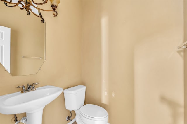 bathroom with an inviting chandelier, sink, and toilet