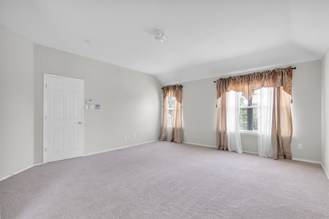 carpeted empty room with lofted ceiling