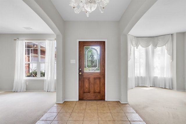 entrance foyer featuring light carpet, a notable chandelier, and a wealth of natural light