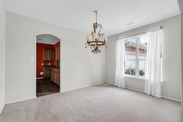 empty room with a chandelier and dark colored carpet