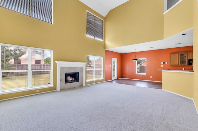 unfurnished living room with carpet, a wealth of natural light, and a high ceiling