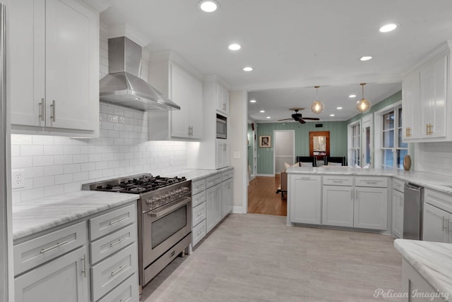 kitchen featuring kitchen peninsula, white cabinetry, wall chimney range hood, and stainless steel appliances