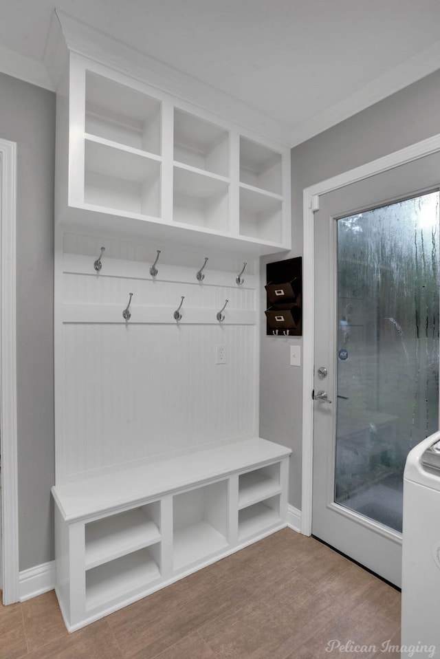 mudroom with washer / clothes dryer, crown molding, and light hardwood / wood-style flooring