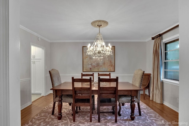 dining room featuring hardwood / wood-style floors, ornamental molding, and a notable chandelier