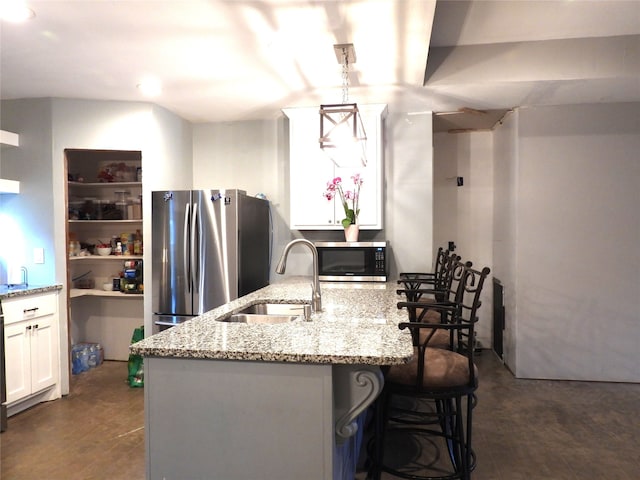 kitchen with white cabinetry, sink, hanging light fixtures, a breakfast bar area, and appliances with stainless steel finishes