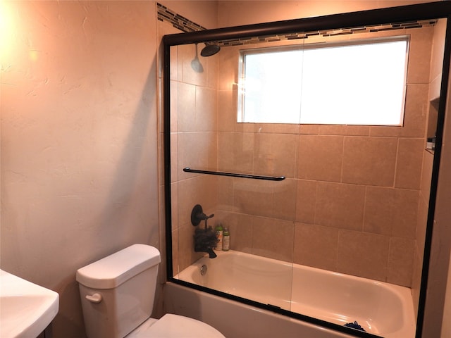 bathroom featuring shower / bath combination with glass door, toilet, and a wealth of natural light