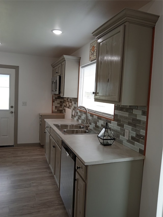 kitchen with wood-type flooring, stainless steel appliances, sink, and decorative backsplash