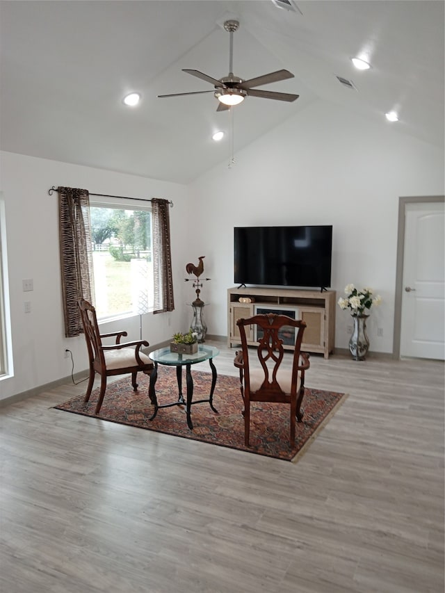 living room featuring vaulted ceiling, light hardwood / wood-style flooring, and ceiling fan