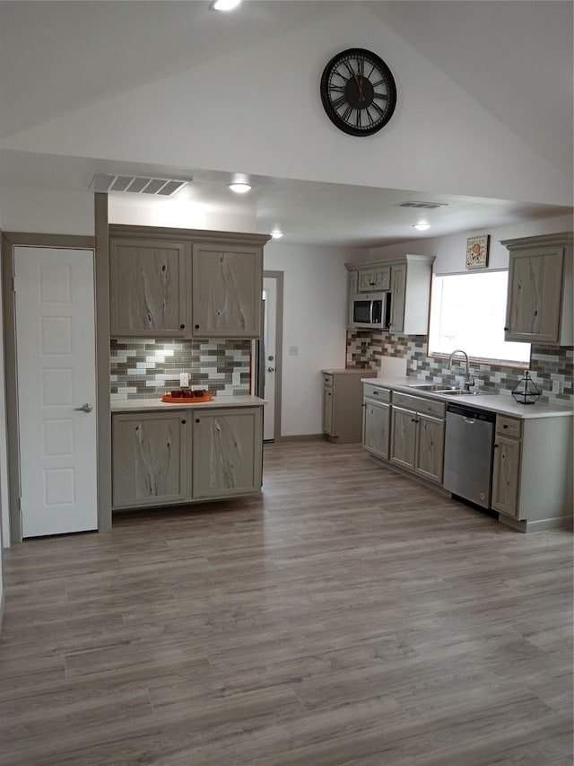 kitchen featuring lofted ceiling, stainless steel appliances, sink, and light wood-type flooring