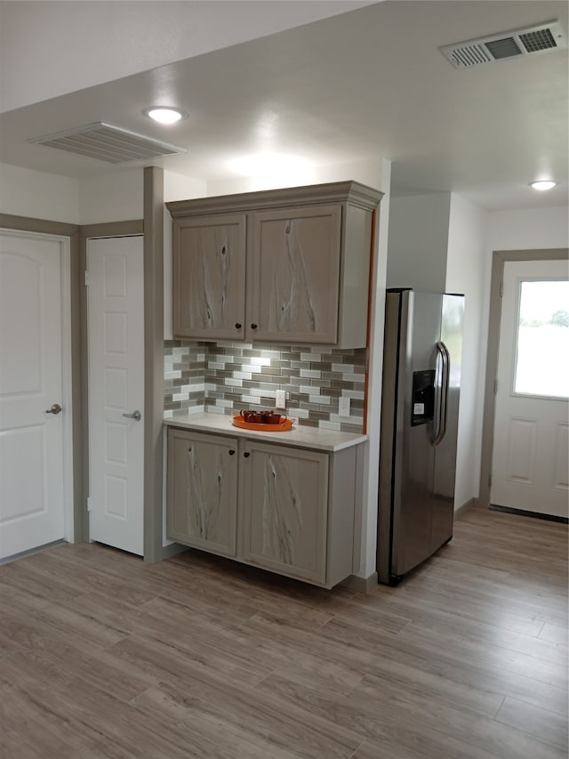 kitchen with light hardwood / wood-style floors, backsplash, and stainless steel fridge with ice dispenser