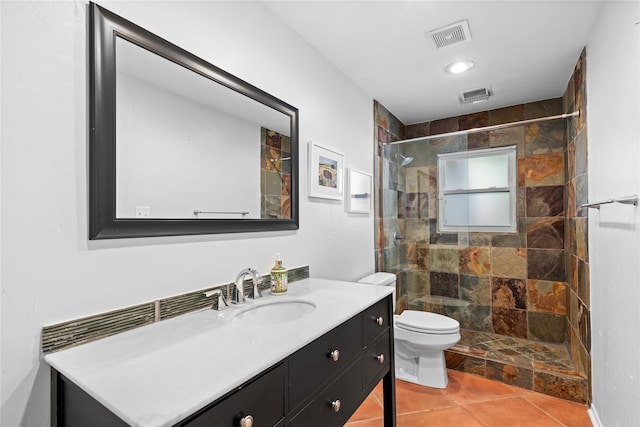 bathroom with tile patterned floors, toilet, a tile shower, and vanity