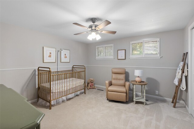 bedroom with light carpet, a nursery area, and ceiling fan