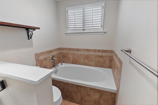 bathroom featuring toilet and a relaxing tiled tub