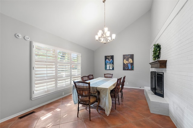 dining space featuring high vaulted ceiling, tile patterned floors, a chandelier, and a fireplace