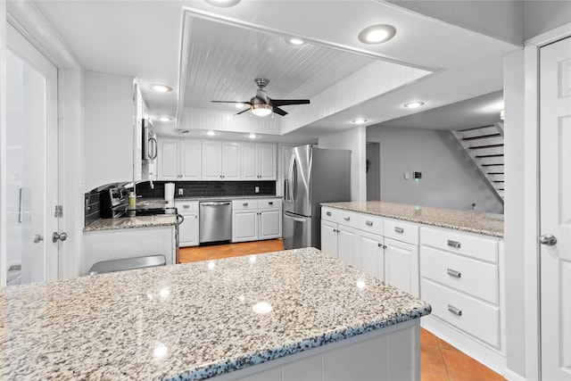 kitchen featuring ceiling fan, stainless steel appliances, white cabinets, and decorative backsplash