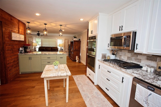 kitchen featuring white cabinetry, green cabinetry, stainless steel appliances, decorative light fixtures, and light hardwood / wood-style floors